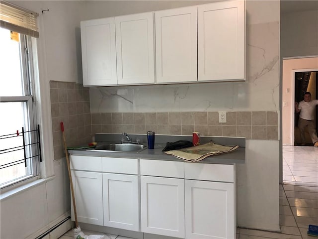 kitchen featuring a sink, baseboard heating, and white cabinetry