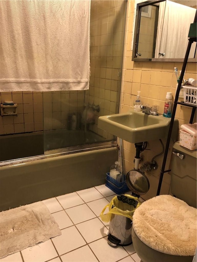 full bathroom with tile patterned floors, a sink, tile walls, and shower / bath combination with glass door