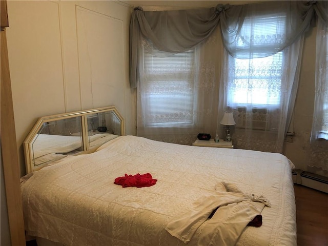 bedroom featuring wood finished floors and baseboard heating