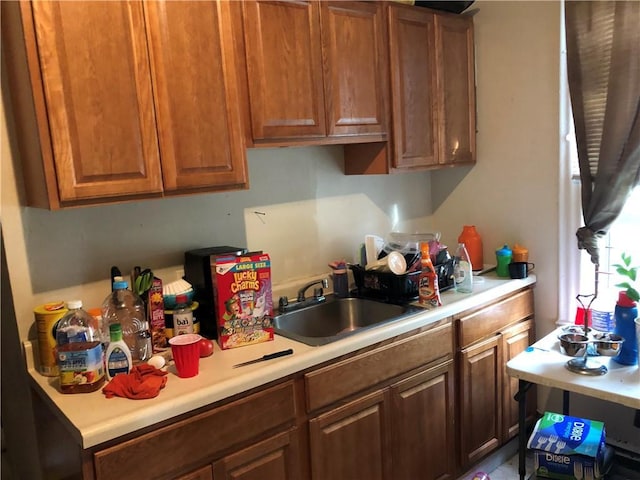 kitchen with light countertops, brown cabinetry, and a sink