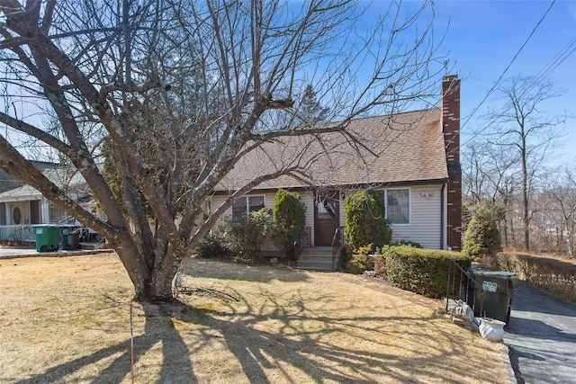 view of front facade with a chimney and a shingled roof