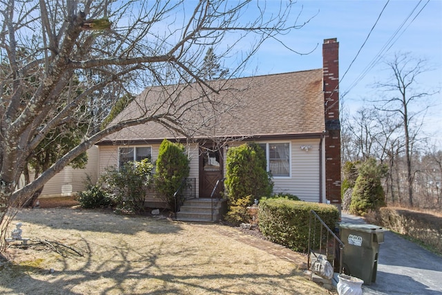 view of front of house with roof with shingles and a chimney