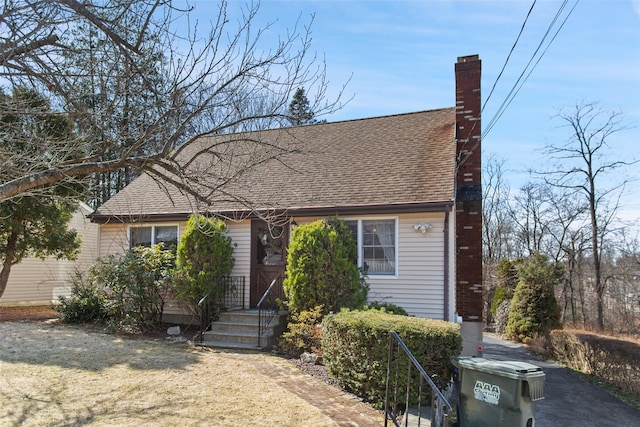 view of front of home featuring a chimney and a shingled roof