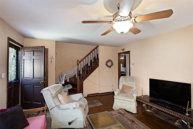 living area featuring a ceiling fan, stairway, and wood finished floors