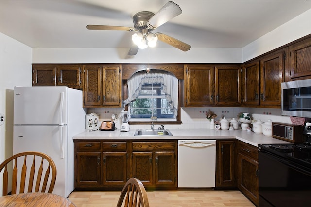 kitchen featuring white appliances, light countertops, and a sink