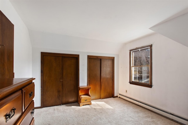 unfurnished bedroom featuring a baseboard heating unit, vaulted ceiling, and light colored carpet