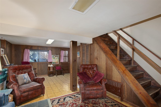 living room featuring stairs, tile patterned floors, and wooden walls