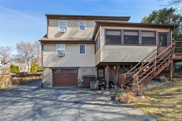 rear view of property featuring aphalt driveway, stairway, an attached garage, and cooling unit