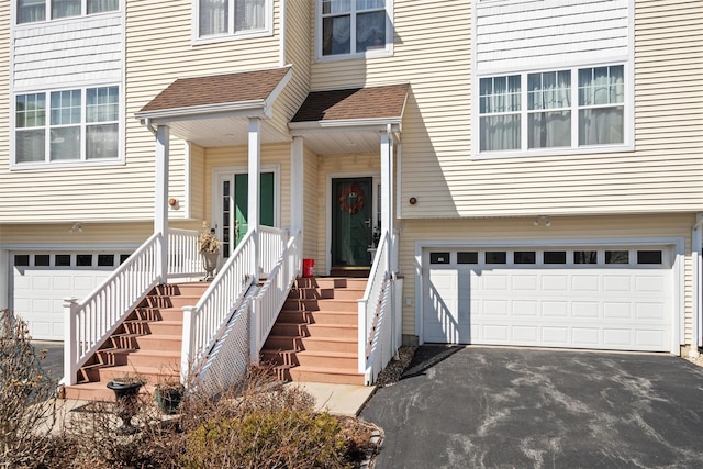 doorway to property featuring aphalt driveway and an attached garage