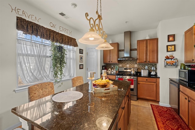 kitchen featuring brown cabinetry, visible vents, stainless steel appliances, wall chimney range hood, and backsplash