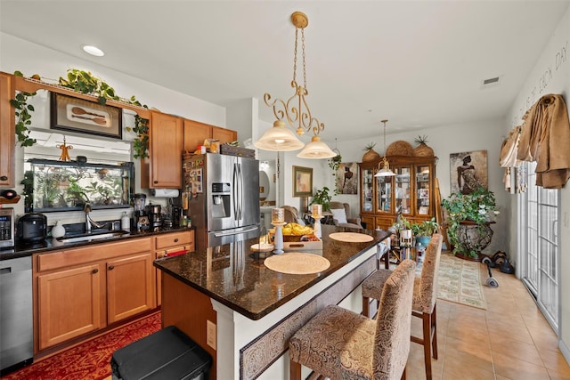 kitchen featuring visible vents, a kitchen bar, a sink, a kitchen island, and appliances with stainless steel finishes