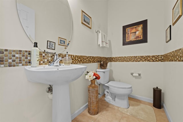 bathroom featuring tile patterned floors, toilet, and tile walls