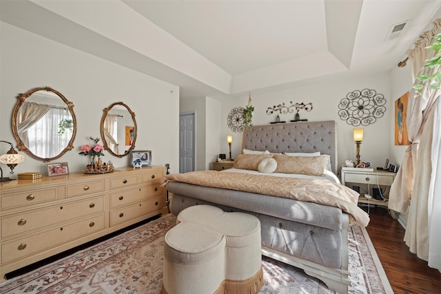 bedroom featuring a raised ceiling, wood finished floors, and visible vents