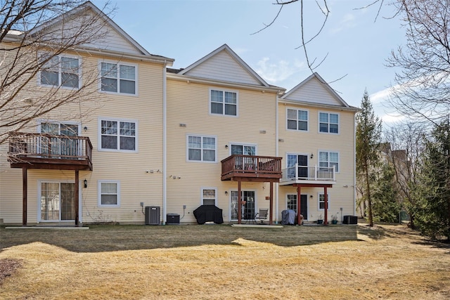 rear view of property with central air condition unit and a yard