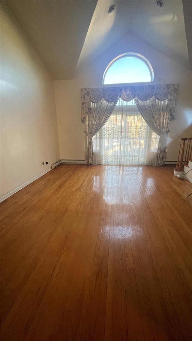 unfurnished living room featuring baseboards, wood-type flooring, lofted ceiling, and stairway