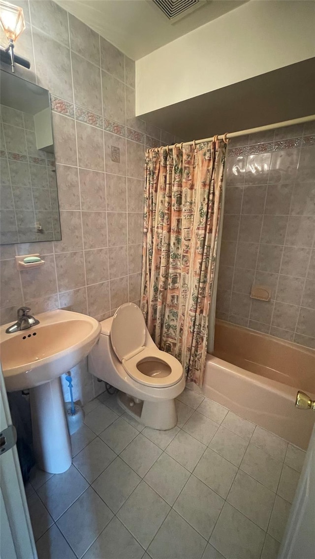 bathroom with visible vents, toilet, shower / tub combo with curtain, tile walls, and tile patterned flooring