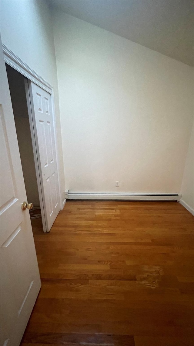 interior space with wood finished floors, a closet, baseboard heating, and baseboards