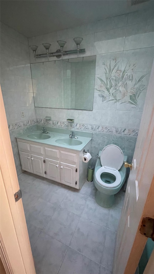 bathroom featuring a sink, toilet, tile walls, and double vanity