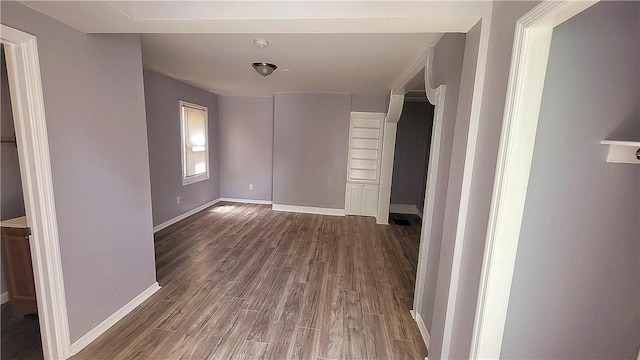 spare room with baseboards and wood finished floors