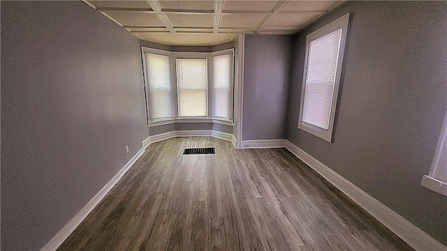 spare room with visible vents, baseboards, dark wood-type flooring, and coffered ceiling