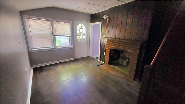 unfurnished living room with a brick fireplace, wood finished floors, baseboards, and vaulted ceiling