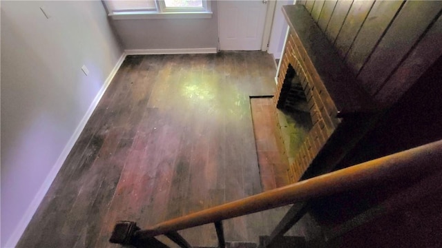 stairway with a brick fireplace, wood finished floors, and baseboards