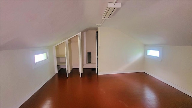 bonus room featuring baseboards, an AC wall unit, and vaulted ceiling