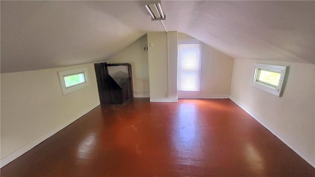 additional living space featuring wood finished floors, a healthy amount of sunlight, baseboards, and lofted ceiling