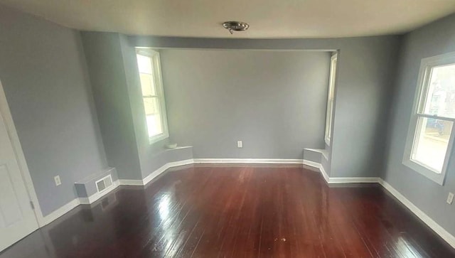 empty room featuring visible vents, baseboards, and wood finished floors