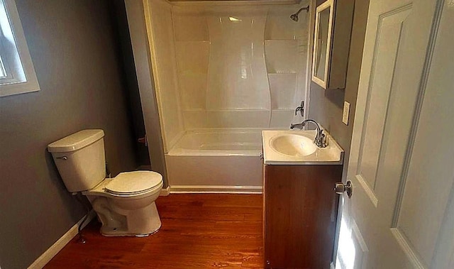 bathroom featuring baseboards, toilet, shower / bathtub combination, wood finished floors, and vanity