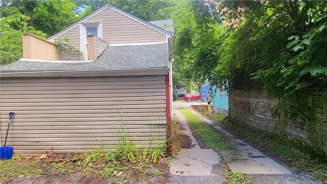 view of home's exterior with driveway and roof with shingles