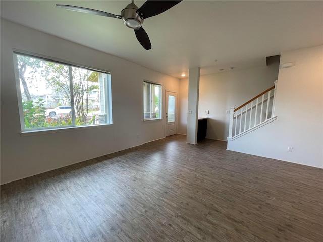 unfurnished living room with stairway, a ceiling fan, and wood finished floors