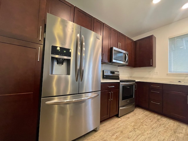 kitchen with dark brown cabinetry, light countertops, light wood-style floors, stainless steel appliances, and a sink