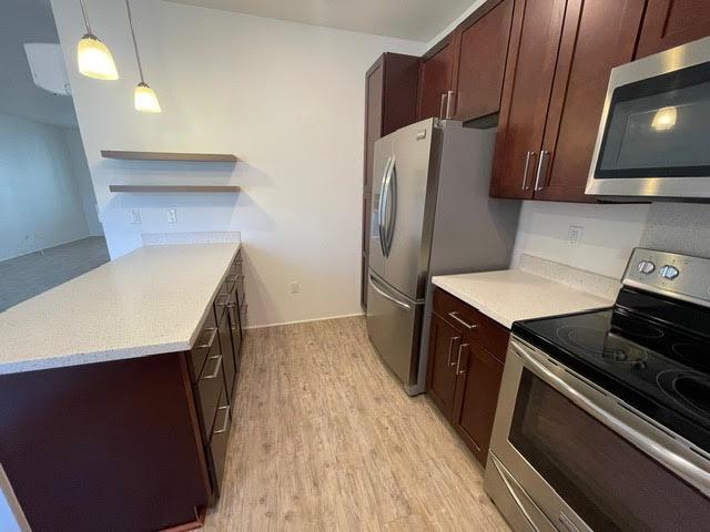 kitchen featuring open shelves, light countertops, light wood-type flooring, and appliances with stainless steel finishes