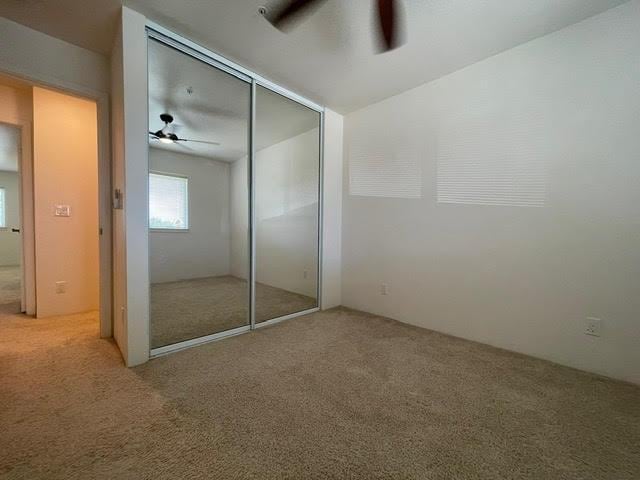 unfurnished bedroom with a closet, a ceiling fan, and carpet