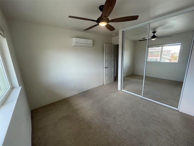 unfurnished bedroom with a closet, a ceiling fan, carpet, and a wall unit AC