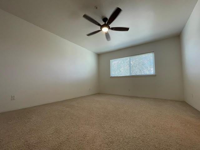 empty room with light colored carpet and a ceiling fan