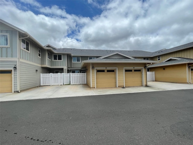 view of property featuring an attached garage, board and batten siding, driveway, and fence