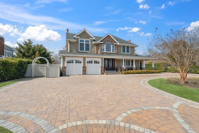 shingle-style home featuring a gate, fence, a porch, an attached garage, and decorative driveway