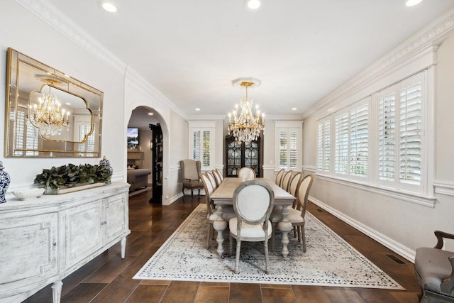 dining space featuring arched walkways, dark wood-type flooring, a chandelier, and ornamental molding