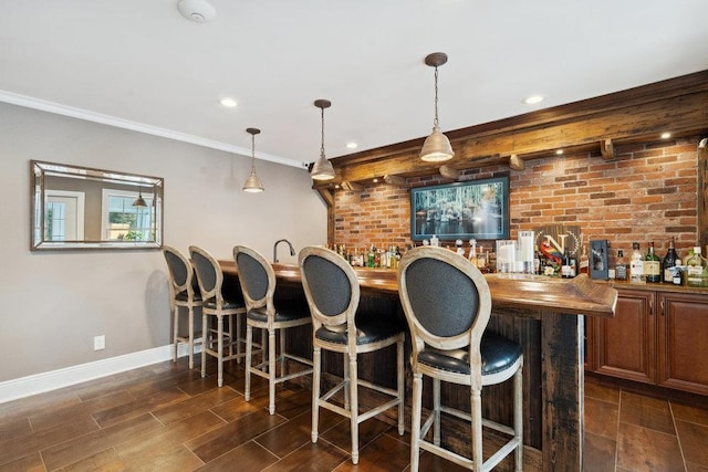 bar featuring indoor wet bar, baseboards, ornamental molding, and wood tiled floor