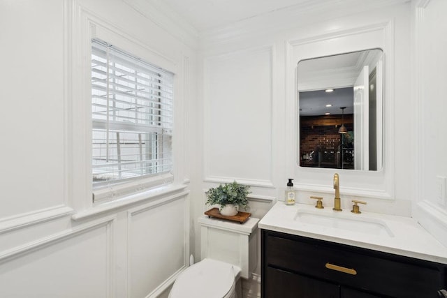 half bath featuring toilet, vanity, and a decorative wall