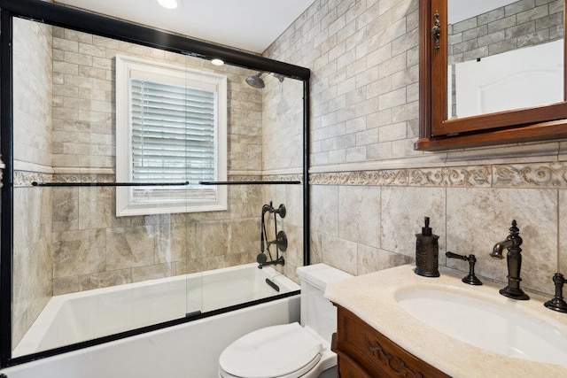 full bath with combined bath / shower with glass door, toilet, tile walls, and vanity