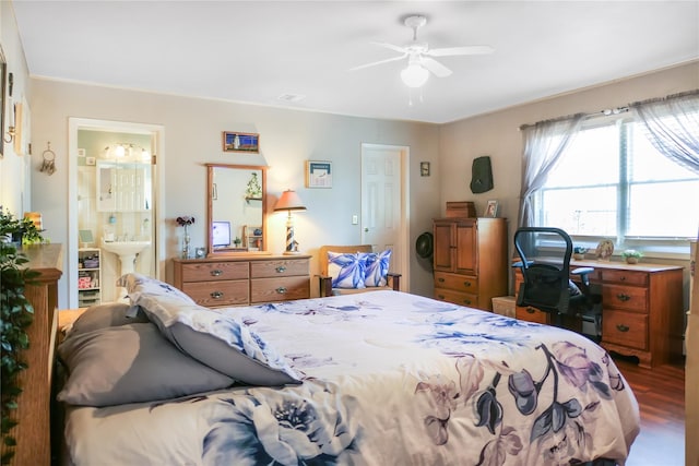 bedroom featuring a ceiling fan, ensuite bath, wood finished floors, and a sink