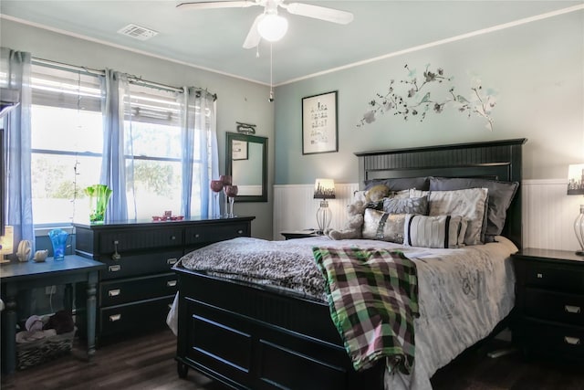 bedroom featuring dark wood finished floors, crown molding, visible vents, and ceiling fan