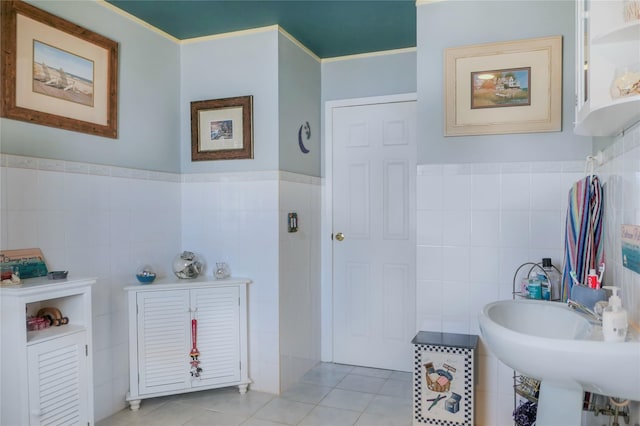 bathroom featuring tile patterned flooring, tile walls, and a sink