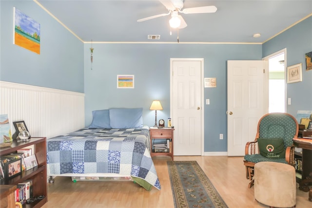 bedroom featuring ceiling fan, visible vents, wood finished floors, and crown molding