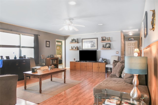 living area featuring a ceiling fan, light wood-type flooring, and baseboards