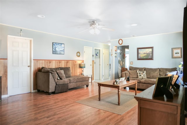 living area featuring a wainscoted wall, light wood-style flooring, and a ceiling fan