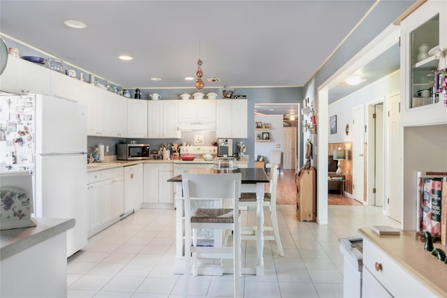 kitchen with light tile patterned floors, white appliances, white cabinets, and light countertops